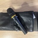 Černý dynamický mikrofon s mřížkou, umístěný na černém koženěném pouzdře. Na těle mikrofonu je zlatý pruh s nápisem PR 20 a bílé logo HEIL. Povrch mi…