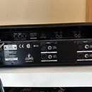 Zadní strana černého elektronického zařízení s nápisem BEHRINGER VINTAGER SERIES. Jsou zde vidět vstupní a výstupní konektory typu XLR s označením IN…