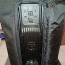 Černý aktivní reproduktor v černé textilní brašně. Na zadním panelu jsou vidět nápisy FIR PHASE, BALANCED INPUT/LINK, PRESETS a VOLUME, dále označení…