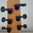 Zadní strana dřevěné hlavy kytary s šesti černými ladicími mechanismy. Na některých z nich je viditelné logo "Gotoh". Povrch dřeva vykazuje v okolí m…