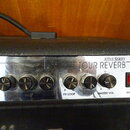 Detail ovládacího panelu kytarového komba s nápisy ATTAX SERIES a TOUR REVERB. Panel obsahuje sedm otočných ovladačů s popisky MASTER, BASS, MID, TRE…