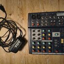 Černý mixovací pult s nápisem Soundcraft Notepad 8FX. Zařízení obsahuje různé vstupy, knoflíky a posuvníky v červené, žluté a modré barvě. Vedle mixe…