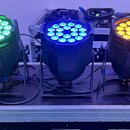 Pět černých LED PAR reflektorů umístěných v řadě na transportním kufru. Každý reflektor svítí jinou barvou: červenou, zelenou, modrou, žlutou a bílou…