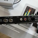 Detail zadní strany stříbrného elektronického zařízení s různými konektory. Jsou zde nápisy Bal.Out, In – 3G - SDI – Through, Phones, L – Line Out –…