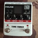 Bílý kytarový efekt s černým ovládacím panelem a červenými popisky. Na panelu jsou nápisy NUX, TSAC TRUE SIMULATION OF ANALOG CIRCUIT a TIME FORCE. J…
