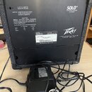 Zadní strana černého přenosného komba s nápisy SOLO™ PORTABLE SOUND SYSTEM a logem Peavey. Na zadním panelu je text s technickými specifikacemi, varo…