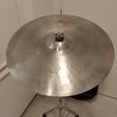 Stříbrný kovový činel umístěný na chromovaném stojanu. Na povrchu je viditelný nápis Zildjian a v horní části menší nápis K. Povrch vykazuje jemné šk…