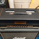 Černý kytarový zesilovač s nápisem CERIATONE AMPLIFICATION na zlatém štítku. Na horní straně je černá rukojeť s kovovými úchyty a dvě mřížkované vent…