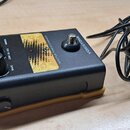 Černý efekt pedál s žlutými dekorativními prvky a nápisy. Na zařízení jsou vidět texty TC HELICON, VOICETONE a ADAPTIVE TONES DYNAMICS. Na horní stra…