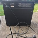 Zadní strana černého kytarového komba značky Marshall. V horní části jsou nápisy Mains Input 230V ~ 50Hz 45 Watts, logo Marshall a varovné texty v ně…