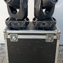 Dvě černé pohyblivé hlavy typu Beam Light umístěné na černém transportním kufru s hliníkovými hranami a kovovými zámky. Na boku každého světla je svi…