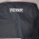 Černý textilní kryt nebo obal s bílým logem FENDER v horní části. Povrch materiálu vykazuje mírné pomačkání a vrásky. Předmět leží na světlé podlaze…