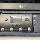 Černý efektový procesor s nápisem AMPERO Amp Modeler / Effects Processor v originální krabici s pěnovou výplní. Zařízení má displej, několik ovládací…