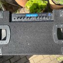 Černý basový kombo zesilovač s povrchem z černého koberce a dvěma plastovými rukojemi po stranách. Na ovládacím panelu je nápis 320 WATT BASS AMPLIFI…