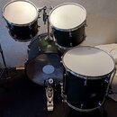 Sada tmavě zelených bubnů s kovovým kováním. Na basovém bubnu a tomu je vidět logo Pearl. Povrchy blan jsou bílé, na levém tomu jsou vidět drobné sto…