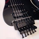 Černá elektrická kytara s černým pickguardem a humbuckerem v pozici u mostu. Nástroj je vybaven černým plovoucím mostem s nápisem Floyd Rose Special.…