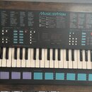 Černý elektronický klavír s bílými a černými klávesami. Na horním panelu je nápis MUSIC STATION, seznamy Voice List a Style List a digitální displej.…