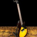 Elektrická kytara s trupem v barevném přechodu od tmavě hnědé k žluté, umístěná na černém stojanu. Na hlavě hmatníku je bílý nápis "Epiphone". Nástro…