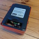 Zadní strana oranžového efekt pedálu s kovovým šasi. Na bílé nálepce jsou nápisy AC ADAPTER DC9V, RoHS, CE a MADE IN CHINA spolu s českým textem o úd…