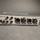Zadní strana černého elektronického zařízení s kovovým šasi. V levém horním rohu je nápis 5015 MIC PRE COMP a vedle konektoru napájení označení 12VDC…