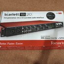 Krabice s USB audio rozhraním Focusrite Scarlett 18i20 druhé generace. Na balení je nápis „Scarlett 18i20“, „2nd generation 18-in/20-out USB audio in…