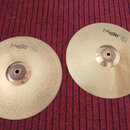 Dvě mosazné činely s žebrovaným povrchem položené na červeném koberci. Oba mají nápis PAiste 302 a označení 14" Hi-Hat. Levý činel má pod tímto nápis…