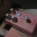 Růžový efekt pedál s nápisem FUZZ a logem Fender. Na horní straně jsou tři bílé otočné knoflíky s čísly 1 až 5 a obrázek postavičky Hello Kitty. Pedá…