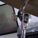 Detailní pohled na chromovaný stojan činely s připevněným mosazným činelem. Na svorečce je vidět logo Pearl a nápis UNI-LOCK SYSTEM. Povrch chromu vy…