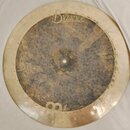 Kruhový mosazný činel s výrazně patinovaným a tmavším středem. V horní části je vidět nápis Byzance a pod ním menší text Made in China. Povrch činelu…