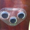 Detail ovládacího panelu s nápisem TransAcoustic. Panel obsahuje tři černé otočné oválné knoflíky s popisky Chorus, Reverb a Lineout Volume. Dole je…