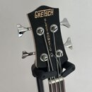 Černá hlava basové kytary s nápisem GRETSCH v horní části a svislým nápisem ELECTROMATIC pod ním. Nástroj má čtyři chromované ladičky. Povrch je hlad…