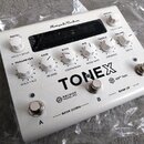 Bílý kytarový pedál s nápisem TONEX a logem AmpliTube v horní části. Obsahuje několik bílých otočných ovladačů s popisky MODEL, PARAMETER, GAIN, BASS…