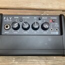 Černý mini zesilovač s nápisem FLY 3 WATT MINI AMP. Na předním panelu jsou čtyři ovládací knofíky s popisky GAIN LEVEL, VOLUME LEVEL, EQ ISF a DELAY…