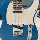 Modrá elektrická kytara s bílým pickguardem a hnedým hmatníkem. Nástroj má jeden snímač typu humbucker v chromovaném rámečku, jeden snímač typu singl…