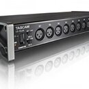 Černý rackový audio rozhraní s kovovými úchyty po stranách. Na přední straně je nápis TASCAM a model US-16x08, přepínače IN 1-4 a IN 5-8, kontrolka U…