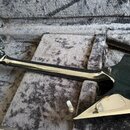 Černá elektrická kytara s ostře hranatým tvarem těla a hlavou v podobě šipky, umístěná v polstrovaném kufru. Na hlavě nástroje je viditelné bílé logo…