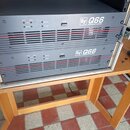 Dvě černé rackové koncové stupně s červenými vodorovnými liniemi na předním panelu. Na obou zařizeních je bílý nápis „Ev Q66 PROFESSIONAL AMPLIFIER“.…