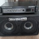 Černý basový zesilovač Hartke LH1000 1000 WATT BASS AMPLIFIER CLASS A VALVE PREAMP položený na černém basovém reproduktoru Hartke HL210 HyDrive. Zesi…