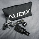 Černý mikrofon s nápisem AUDIX D2, černý držák na mikrofon a černý textilní zipový sáček s bílým nápisem AUDIX. Všechny předměty jsou umístěny na šed…