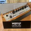 Fotografie znázorňuje kartónovou krabici s obrázkem kytarového komba. Na spodní černé části je bílý nápis ORANGE AMPLIFICATION a model CRUSH 35RT GUI…