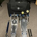 Sada kovových bubnových pedálů v modré a stříbrné barvě s logem YAMAHA. Součástí je černá přepravní taška s bílým logem Yamaha, dvě žluté gumové podl…