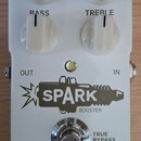 Bílý kytarový pedál s nápisy SPARK BOOSTER a tc electronic. Obsahuje čtyři bílé otočné ovladače s popisky BASS, TREBLE a dvěma nečitelnými nápisy v h…