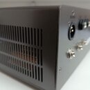 Černý kovový box s ventilačními otvory na boční straně. Na zadním panelu jsou umístěny tři konektory, včetně jednoho XLR vstupu. V horní části panelu…