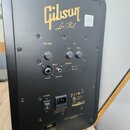 Zadní strana černého reproduktoru s nápisem Gibson Les Paul. Na horním panelu jsou ovladače VOLUME, BASS a TREBLE pod nadpisem EQ, dále vstupy INPUT…