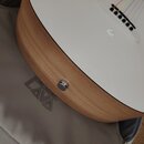 Detail akustické kytary s bílou horní deskou a bočnicemi v imitaci světlého dřeva. Na bílém povrchu je vidět malé logo ve tvaru stylizovaného písmene…