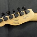 Zadní strana hlavy kytary z přírodního dřeva s šesti černými ladicími kolíky. Na dřevě je nápis esigned and Backed by Fender®, Crafted in China a s/n…