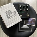 Černý efekt pedál s nápisy MEGALITH, ENGAGE, MORE HEAVY a MOUNTAINKING ELECTRONICS. Pedál má pět ovládacích knoflíků, dva spínače a nápisy MORE, DRIV…
