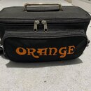 Černá textilní přepravní taška s kovovou rukojetí na horní straně. Na přední části je oranžový nápis ORANGE. Taška má zipové uzavírání a boční popruh…