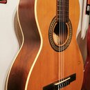Kytara s nylonovými strunami, světlým topem a tmavě hnědými boky a zadní stranou. Kolem otvoru rezonátoru je dekorativní rozeta s geometrickým vzorem…