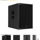 Černý aktivní subwoofer s hranatým tvarem a kovovou ochrannou mřížkou v přední části. Na spodní části mřížky je umístěno malé čtvercové logo RCF. Na…